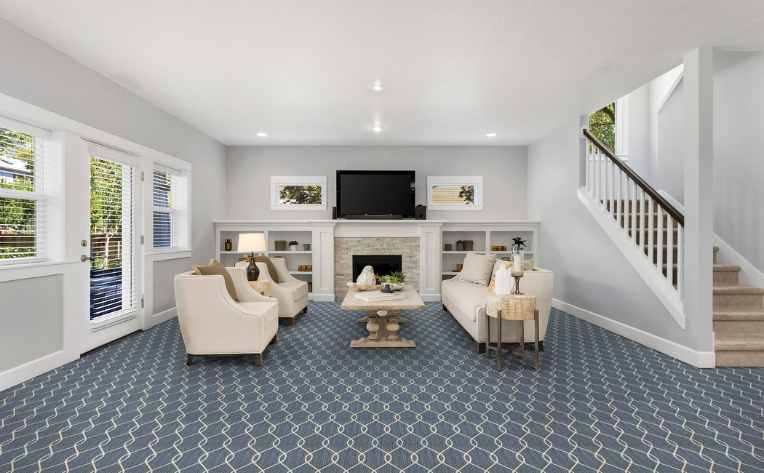 blue patterned carpet in family room with carpeted stairs leading down